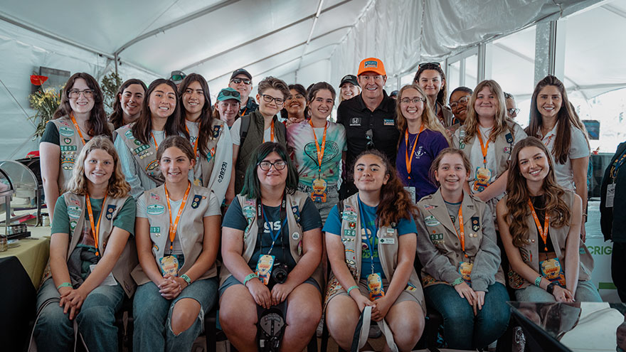 Scott Dixon posando con un grupo de Girl Scouts en Mujeres jóvenes en el día de carrera
